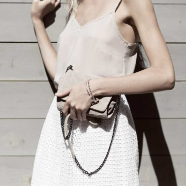 A woman holding onto her purse while wearing a white dress