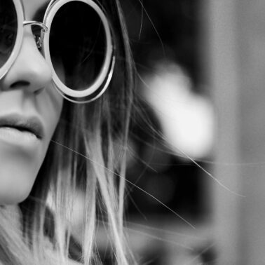 A woman wearing round sunglasses and a long blonde hair.